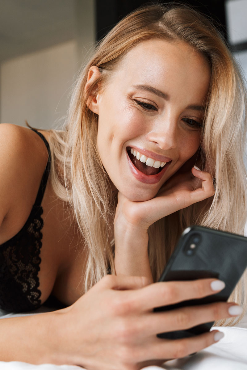 Blond woman looking happily at her phone